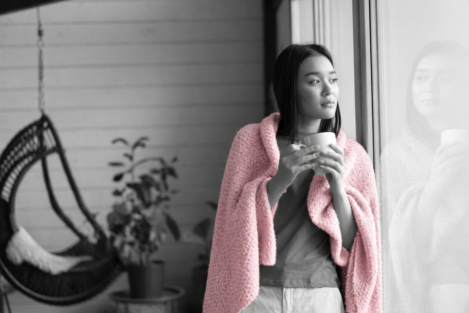 Woman gazing out a window holding a cup of coffee