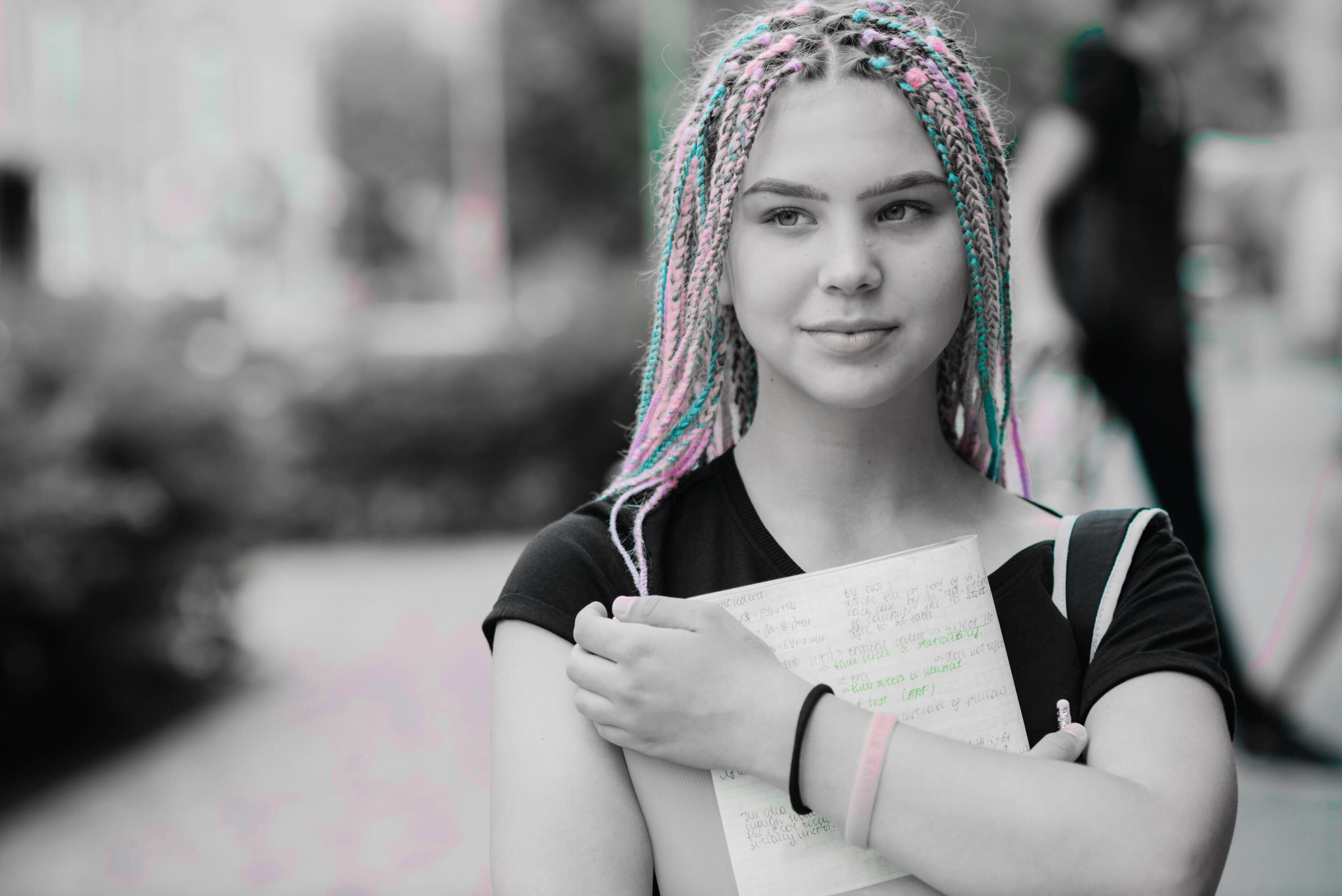 Young woman with colorful braids holding a notebook